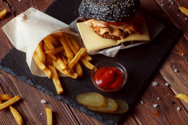 Ahşap arka planda patates kızartmalı hamburger.