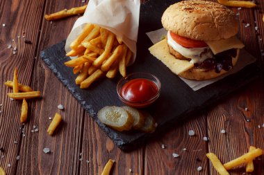 Ahşap arka planda patates kızartmalı hamburger.