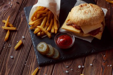Ahşap arka planda patates kızartmalı hamburger.