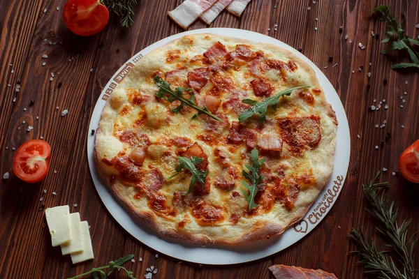 Tahta bir masada etli ve sebzeli pizza. 