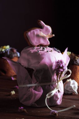 Bayram masasında Paskalya pastası. Koyu odunsu arka planda coşkulu bahar renkleri olan şenlikli pişmiş yiyecekler. Kompozisyonun dekorunda kurumuş çiçekler.