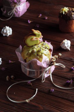 Bayram masasında Paskalya pastası. Koyu odunsu arka planda coşkulu bahar renkleri olan şenlikli pişmiş yiyecekler. Kompozisyonun dekorunda kurumuş çiçekler.