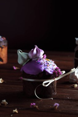 Bayram masasında Paskalya pastası. Koyu odunsu arka planda coşkulu bahar renkleri olan şenlikli pişmiş yiyecekler. Kompozisyonun dekorunda kurumuş çiçekler.