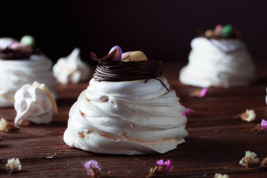 Bayram masasında Paskalya pastası. Koyu odunsu arka planda coşkulu bahar renkleri olan şenlikli pişmiş yiyecekler. Kompozisyonun dekorunda kurumuş çiçekler.