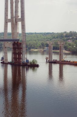 Concrete bridge over the river. Complex technical projects. A large architectural structure under construction. Temporary iron piles for the construction of columns. Large industrial equipment.
