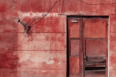 Kırmızı ve kahverengi boyalı paslı demir kapı.
