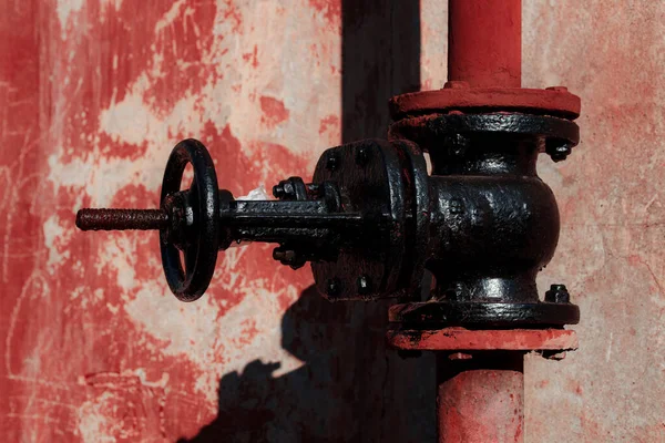 Kırmızı tuğlalı bir duvarın arka planında paslı metal bir dambıl.