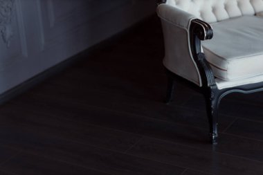 Koyu ahşap saplı, çerçeveli ve beyaz yorganlı beyaz renkli kanepe. Eski bir iç mekan konsepti.