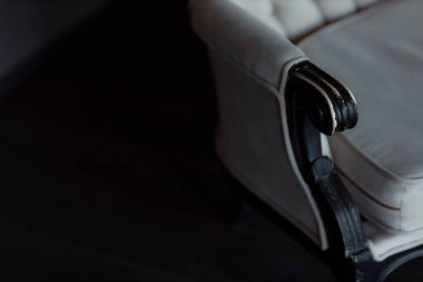 Koyu ahşap saplı, çerçeveli ve beyaz yorganlı beyaz renkli kanepe. Eski bir iç mekan konsepti.