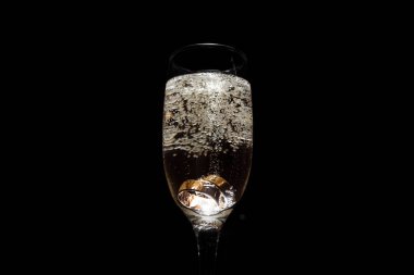 Siyah arka planda alyansı olan bir kadeh şampanya. 