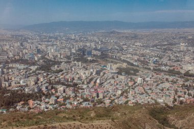 TBILISI, GEORGIA - 9 AĞUSTOS 2021: Dağlık arazili kırmızı tuğlalı evlerin olduğu eski şehir manzarası.