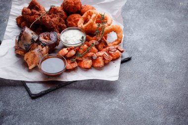 Siyah arka planı olan tabakta taze deniz ürünleri.