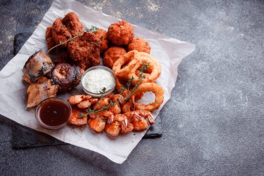 Orijinal et yemeği servisi. Kızarmış tavuk kanadı ve but. Kızarmış peynir topları, ızgara sosis, biberiye ve ketçap. Açık hava yemekleri için yiyecek..