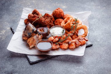 Orijinal et yemeği servisi. Kızarmış tavuk kanadı ve but. Kızarmış peynir topları, ızgara sosis, biberiye ve ketçap. Açık hava yemekleri için yiyecek..