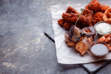 Orijinal et yemeği servisi. Kızarmış tavuk kanadı ve but. Kızarmış peynir topları, ızgara sosis, biberiye ve ketçap. Açık hava yemekleri için yiyecek..