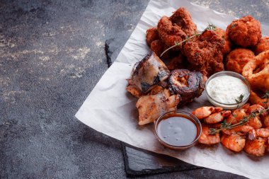 Orijinal et yemeği servisi. Kızarmış tavuk kanadı ve but. Kızarmış peynir topları, ızgara sosis, biberiye ve ketçap. Açık hava yemekleri için yiyecek..