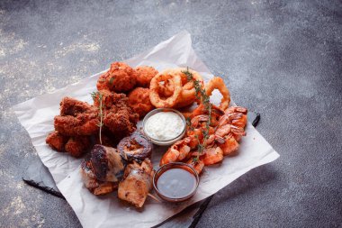 Orijinal et yemeği servisi. Kızarmış tavuk kanadı ve but. Kızarmış peynir topları, ızgara sosis, biberiye ve ketçap. Açık hava yemekleri için yiyecek..