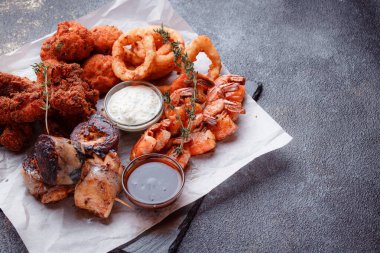 Orijinal et yemeği servisi. Kızarmış tavuk kanadı ve but. Kızarmış peynir topları, ızgara sosis, biberiye ve ketçap. Açık hava yemekleri için yiyecek..