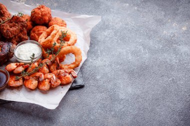 Orijinal et yemeği servisi. Kızarmış tavuk kanadı ve but. Kızarmış peynir topları, ızgara sosis, biberiye ve ketçap. Açık hava yemekleri için yiyecek..