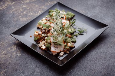 Pastırmalı yaz salatası, salatalık, peynir kübü ve mantar. Siyah tabakta yeşil salata, siyah arka planda. Bir yazı için boş yer. Yukarıdan görüntüle.