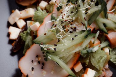 Pastırmalı yaz salatası, salatalık, peynir kübü ve mantar. Siyah tabakta yeşil salata, siyah arka planda. Bir yazı için boş yer. Yukarıdan görüntüle.