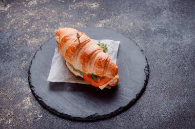 Taze lahana, kırmızı domates, prosciutto, peynir dilimi ve soğanla doldurulmuş kruvasan. Yolculuk için fast food. Benzin istasyonunda yemek hazır. Bir fırının reklamını yapmak için..