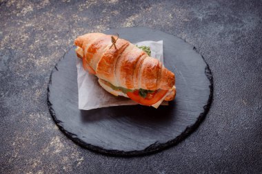 Taze lahana, kırmızı domates, prosciutto, peynir dilimi ve soğanla doldurulmuş kruvasan. Yolculuk için fast food. Benzin istasyonunda yemek hazır. Bir fırının reklamını yapmak için..