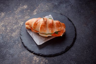 Taze lahana, kırmızı domates, prosciutto, peynir dilimi ve soğanla doldurulmuş kruvasan. Yolculuk için fast food. Benzin istasyonunda yemek hazır. Bir fırının reklamını yapmak için..