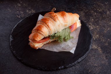 Taze lahana, kırmızı domates, prosciutto, peynir dilimi ve soğanla doldurulmuş kruvasan. Yolculuk için fast food. Benzin istasyonunda yemek hazır. Bir fırının reklamını yapmak için..