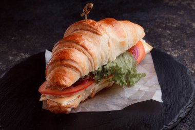 Taze lahana, kırmızı domates, prosciutto, peynir dilimi ve soğanla doldurulmuş kruvasan. Yolculuk için fast food. Benzin istasyonunda yemek hazır. Bir fırının reklamını yapmak için..