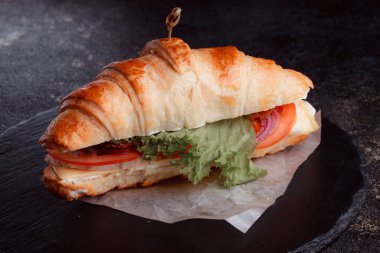 Taze lahana, kırmızı domates, prosciutto, peynir dilimi ve soğanla doldurulmuş kruvasan. Yolculuk için fast food. Benzin istasyonunda yemek hazır. Bir fırının reklamını yapmak için..