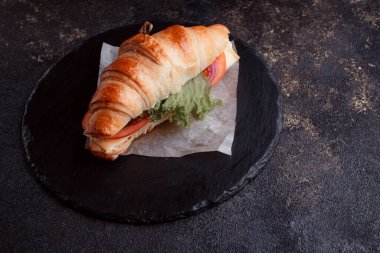 Taze lahana, kırmızı domates, prosciutto, peynir dilimi ve soğanla doldurulmuş kruvasan. Yolculuk için fast food. Benzin istasyonunda yemek hazır. Bir fırının reklamını yapmak için..