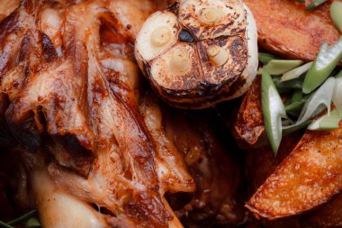 Kemiğin üzerinde büyük bir parça kızarmış et. Josper 'da kızartılmış sarımsak. Büyük parçalar halinde ızgara patates..