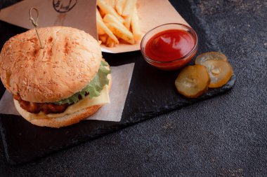 Lezzetli ev yapımı hamburger ızgara sığır eti, domates, peynir, salatalık ve ahşap masada sos..