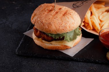 Lezzetli ev yapımı hamburger ızgara sığır eti, domates, peynir, salatalık ve ahşap masada sos..