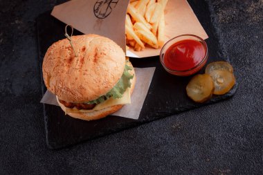 Lezzetli ev yapımı hamburger ızgara sığır eti, domates, peynir, salatalık ve ahşap masada sos..