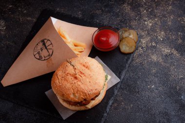 Lezzetli ev yapımı hamburger ızgara sığır eti, domates, peynir, salatalık ve ahşap masada sos..