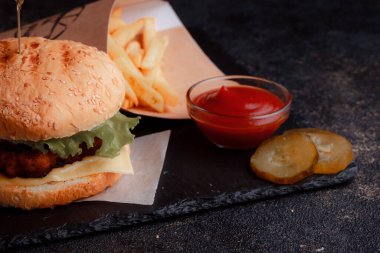 Lezzetli ev yapımı hamburger ızgara sığır eti, domates, peynir, salatalık ve ahşap masada sos..