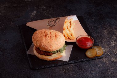 Lezzetli ev yapımı hamburger ızgara sığır eti, domates, peynir, salatalık ve ahşap masada sos..