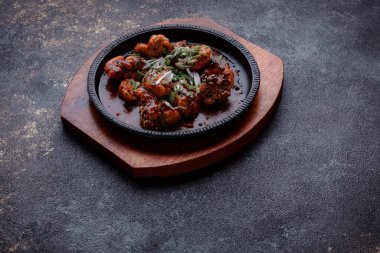 Kızarmış et ve karamelli soslu sıcak tava. Pişirilmiş ve garnitür olarak taze sebzeler. Keten tohumu ve susam tohumu eklenmiş bir yemek..