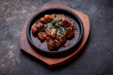 Kızarmış et ve karamelli soslu sıcak tava. Pişirilmiş ve garnitür olarak taze sebzeler. Keten tohumu ve susam tohumu eklenmiş bir yemek..