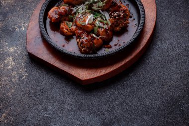 Kızarmış et ve karamelli soslu sıcak tava. Pişirilmiş ve garnitür olarak taze sebzeler. Keten tohumu ve susam tohumu eklenmiş bir yemek..