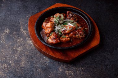 Kızarmış et ve karamelli soslu sıcak tava. Pişirilmiş ve garnitür olarak taze sebzeler. Keten tohumu ve susam tohumu eklenmiş bir yemek..