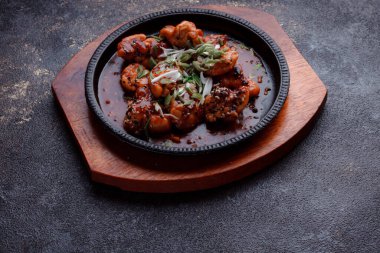 Kızarmış et ve karamelli soslu sıcak tava. Pişirilmiş ve garnitür olarak taze sebzeler. Keten tohumu ve susam tohumu eklenmiş bir yemek..