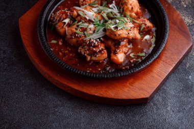 Kızarmış et ve karamelli soslu sıcak tava. Pişirilmiş ve garnitür olarak taze sebzeler. Keten tohumu ve susam tohumu eklenmiş bir yemek..