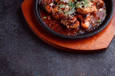 Kızarmış et ve karamelli soslu sıcak tava. Pişirilmiş ve garnitür olarak taze sebzeler. Keten tohumu ve susam tohumu eklenmiş bir yemek..