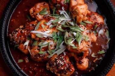 Kızarmış et ve karamelli soslu sıcak tava. Pişirilmiş ve garnitür olarak taze sebzeler. Keten tohumu ve susam tohumu eklenmiş bir yemek..