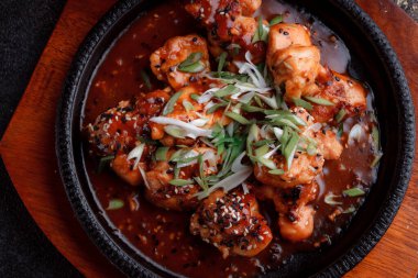 Kızarmış et ve karamelli soslu sıcak tava. Pişirilmiş ve garnitür olarak taze sebzeler. Keten tohumu ve susam tohumu eklenmiş bir yemek..