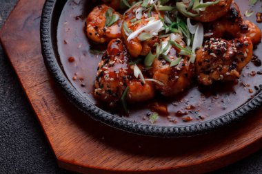 Kızarmış et ve karamelli soslu sıcak tava. Pişirilmiş ve garnitür olarak taze sebzeler. Keten tohumu ve susam tohumu eklenmiş bir yemek..