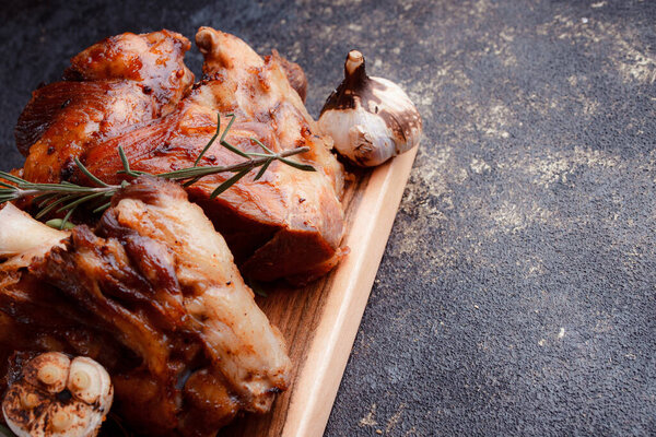 A large piece of fried meat on the bone close-up. Sliced garlic fried on a josper. Grilled potatoes in large chunks.